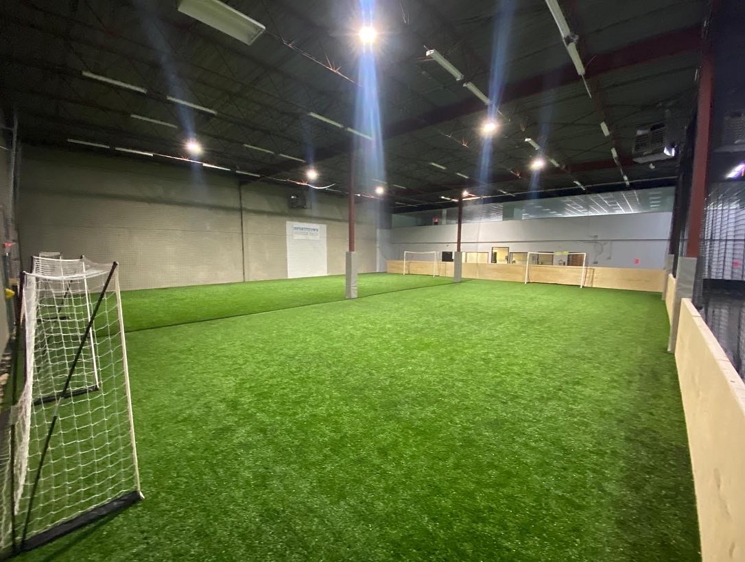 A soccer field with lights on the ceiling.